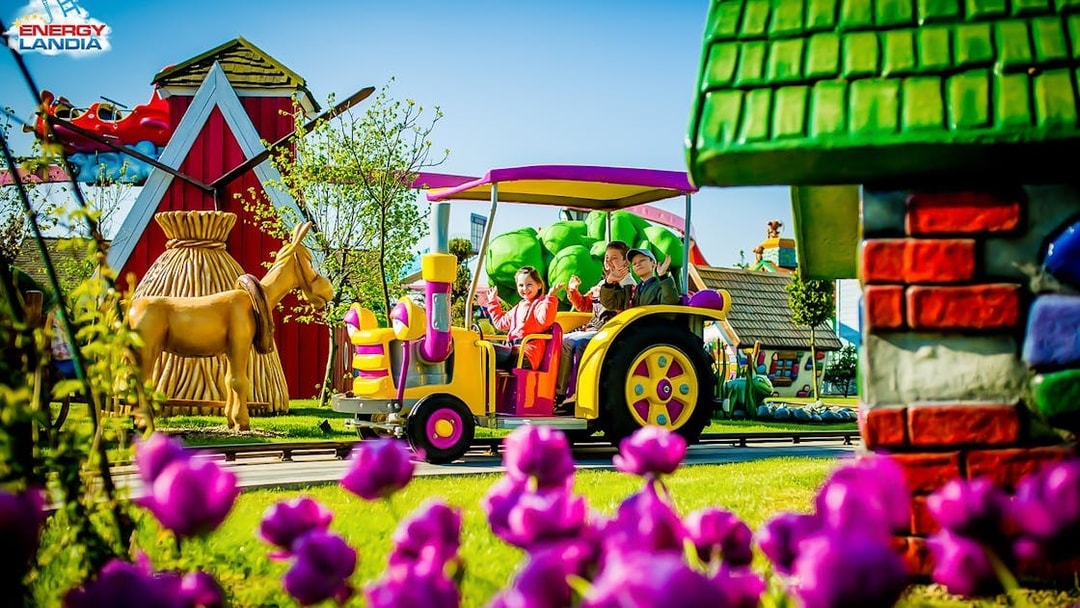 Children riding a colorful tractor ride at Energylandia Amusement Park.