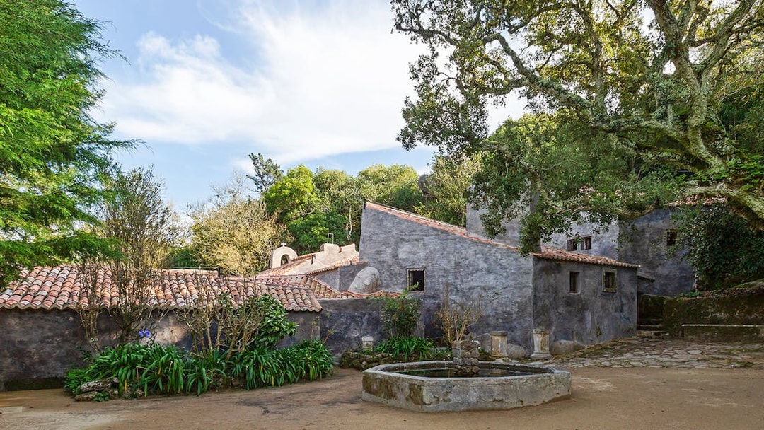 Convento dos Capuchos courtyard with stone buildings and lush greenery in Sintra, Portugal.