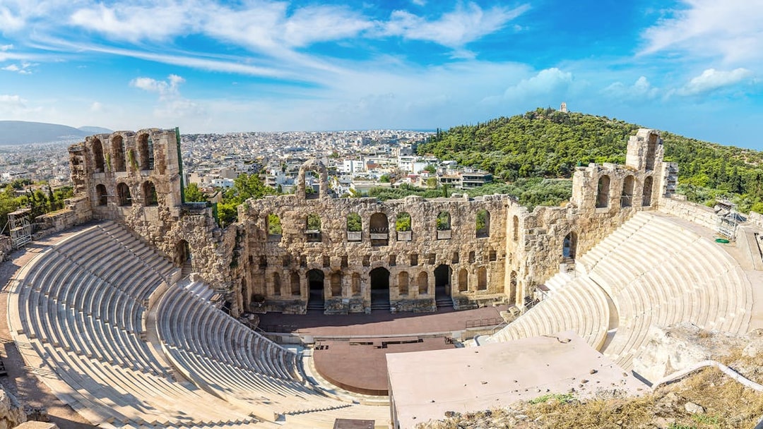 Ancient Odeon of Herodes Atticus amphitheater in Athens, Greece, with cityscape in the background.