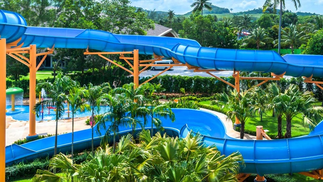 Blue water slide at Splash Jungle Waterpark surrounded by tropical greenery.