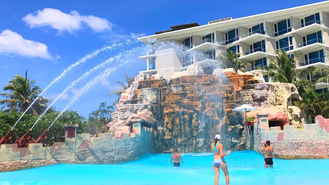 Visitors enjoying the wave pool at Splash Jungle Waterpark with water jets and rock formations.