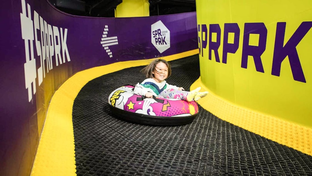 Girl sliding on colorful air tube at SuperPark, Malaysia indoor playground.