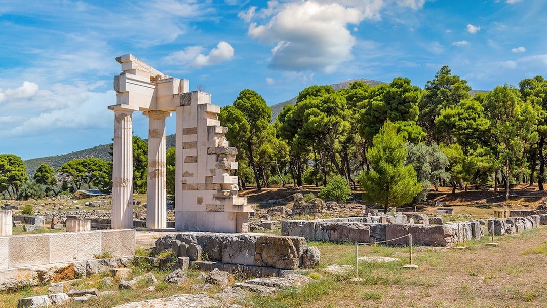 Epidaurus Ancient Theatre ruins with surrounding greenery and blue sky.