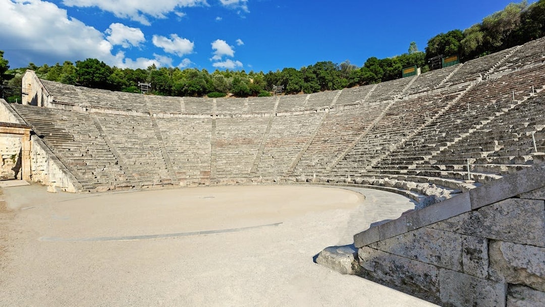 Epidaurus Ancient Theatre with stone seating and stage under a blue sky.