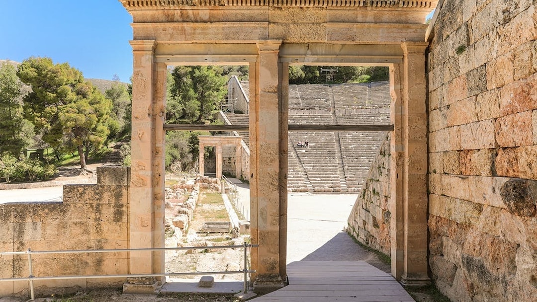 Epidaurus Ancient Theatre entrance with stone seating and surrounding greenery.