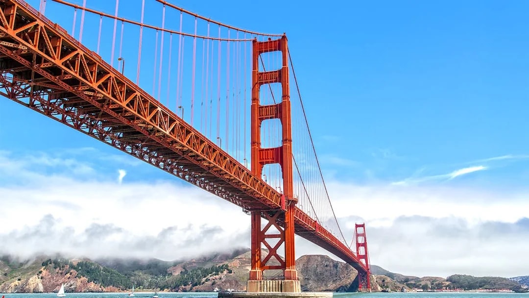 Golden Gate Bridge view from a ferry in San Francisco with hills in the background.