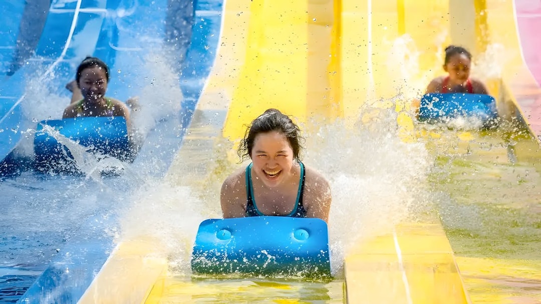 Water slides at Escape Penang water park with people enjoying the ride.