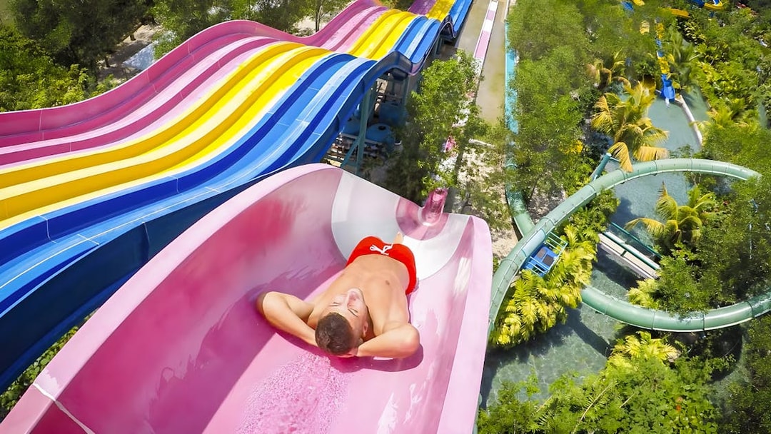 Man sliding down a colorful water slide at Escape Penang water park.