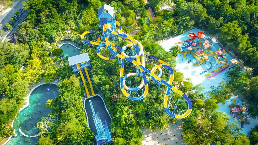 Aerial view of water slides and pools at Escape Penang water park surrounded by lush greenery.