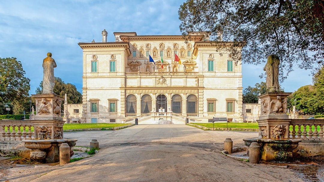 Villa Borghese facade with statues and trees during sunset in Rome, Italy.