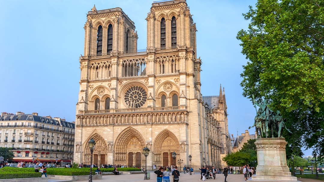 Notre Dame Cathedral facade with nearby statue during Paris walking tour.