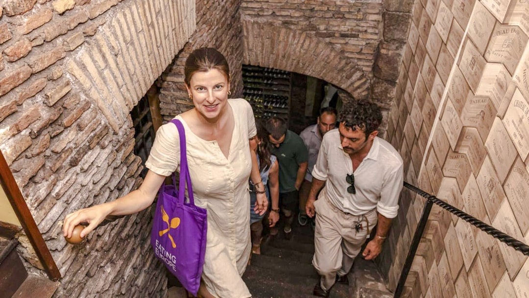 Visitors ascending stairs in ancient wine cellar on Rome food tour.