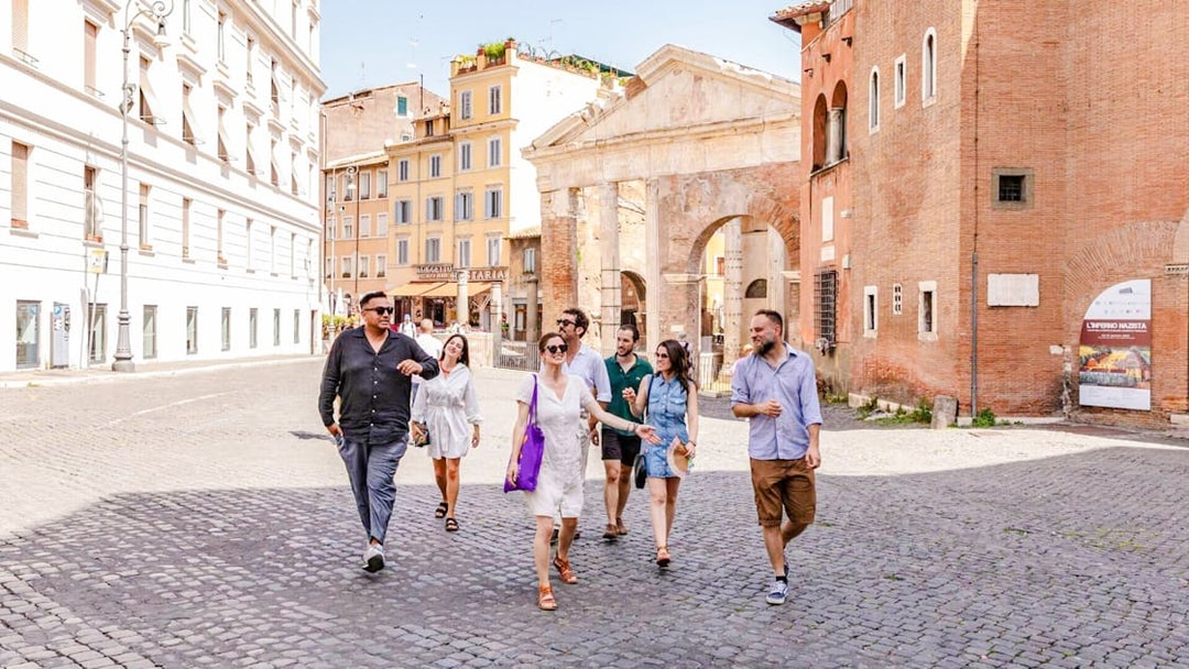 Tour group walking through the Jewish Ghetto neighborhood with ancient architecture in the background.