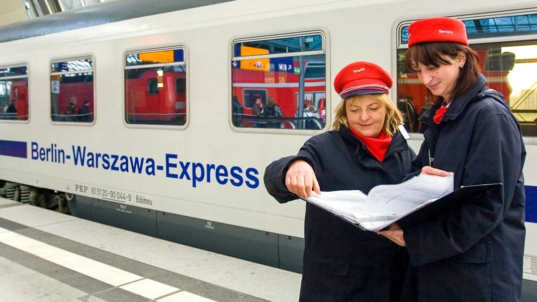 Berlin-Warsaw Express staff discussing schedules on the platform.