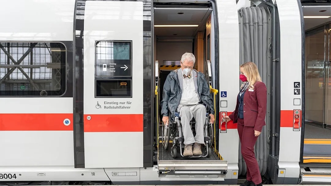 Man in wheelchair exiting train with assistance in Germany.
