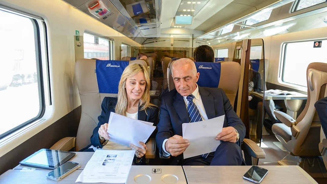 Passengers reviewing documents in first-class seats on a Trenitalia train with Eurail Global Pass.