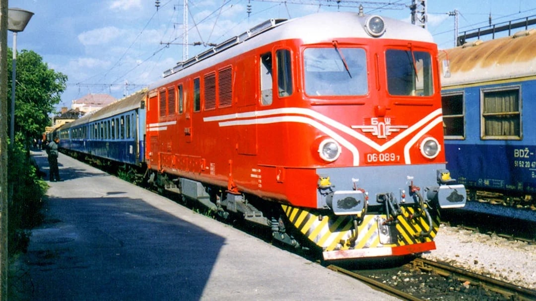 Red and blue train at a station, representing Eurail Global Flexible Pass with 1st Class Seats.