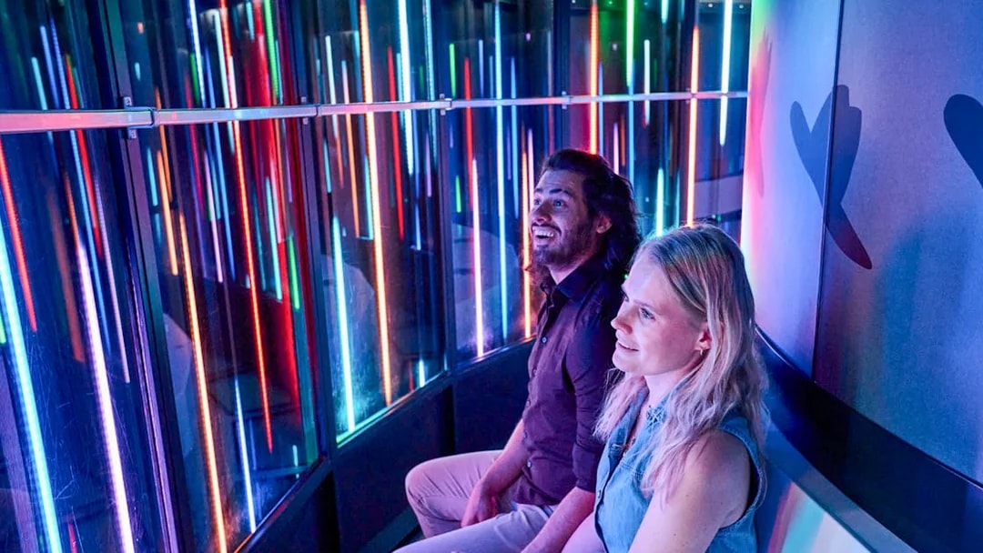 Visitors enjoying the colorful light display inside the Euroscoop at Euromast Lookout.