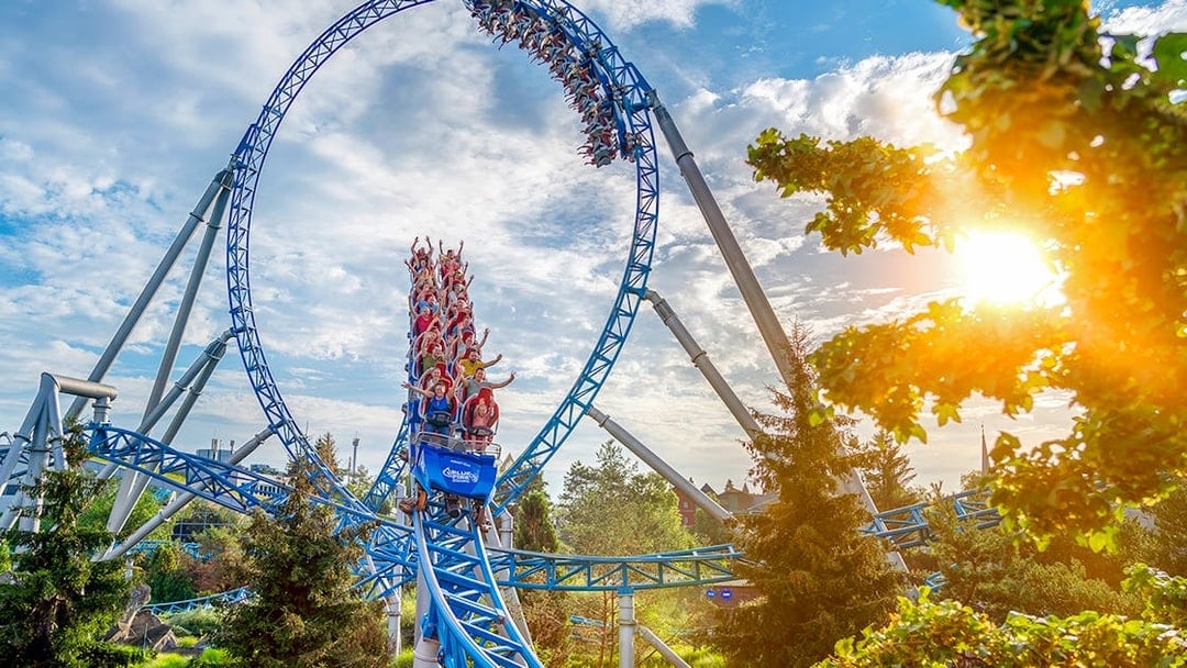 Roller coaster loop with riders at Europa-Park under a sunny sky.