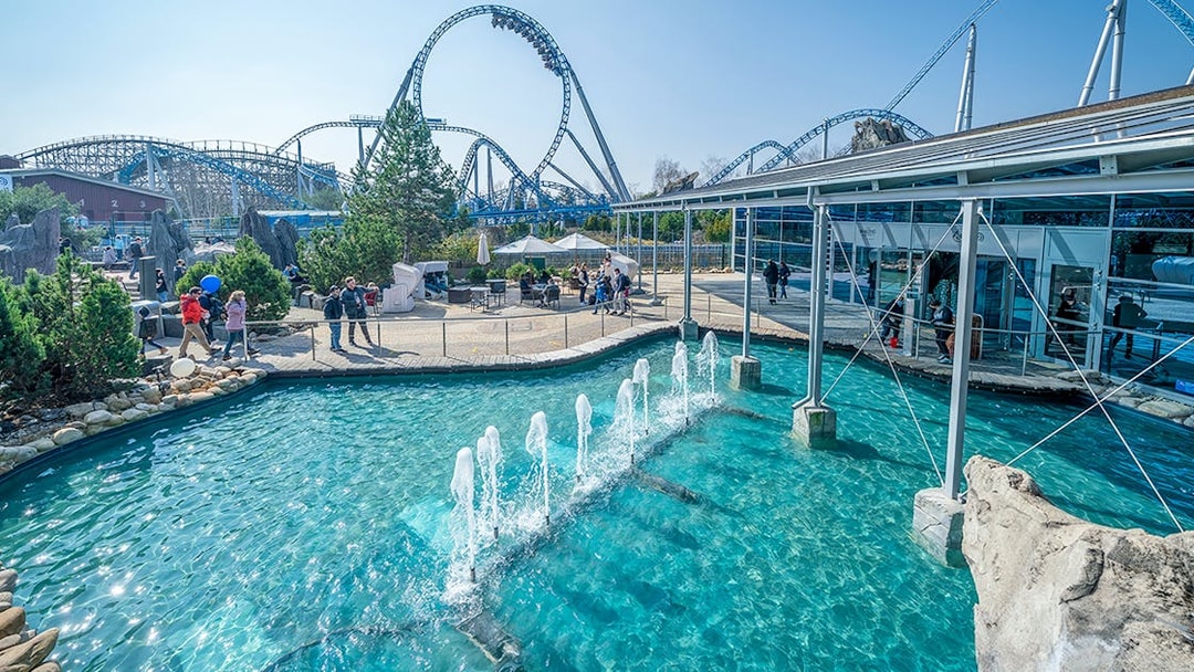 Atlantica SuperSplash ride with fountains and roller coaster in the background.