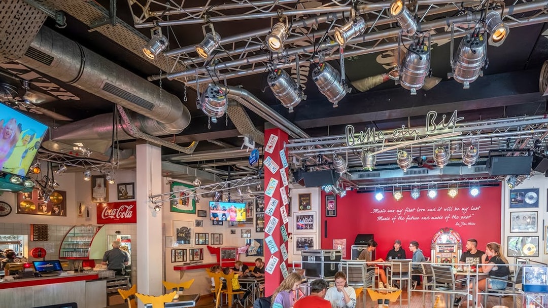 Indoor dining area at Europa-Park with guests seated, vibrant decor, and stage lighting.