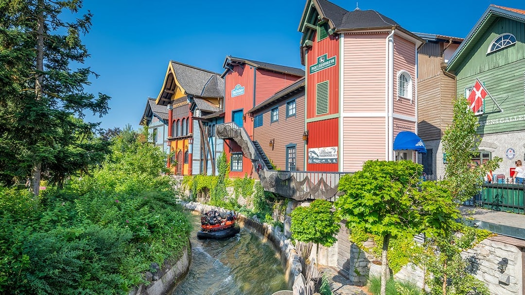Group enjoying a thrilling Fjord Rafting ride past colorful buildings and lush greenery.