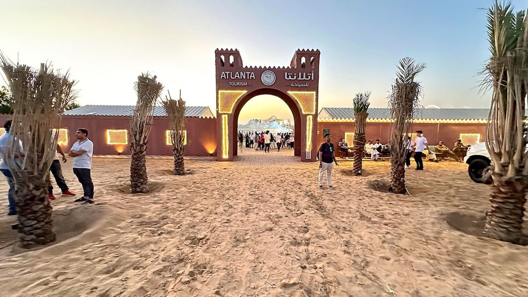 Desert safari entrance with people gathering at sunset, Dubai.