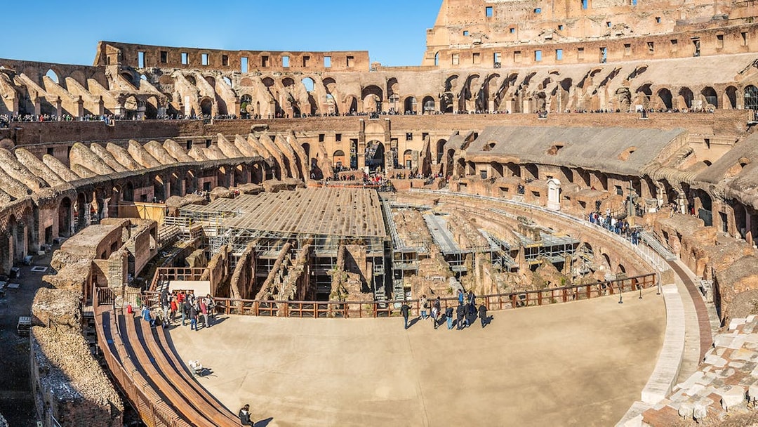 Colosseum interior with tourists exploring ancient amphitheater in Rome, Italy.
