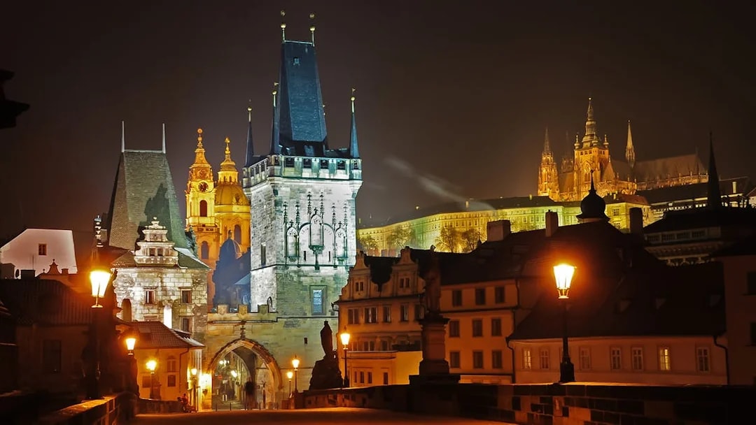 Charles Bridge at night with Prague Castle illuminated in the background.