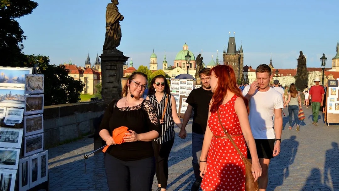 Tourists walking on Charles Bridge in Prague during an evening tour.
