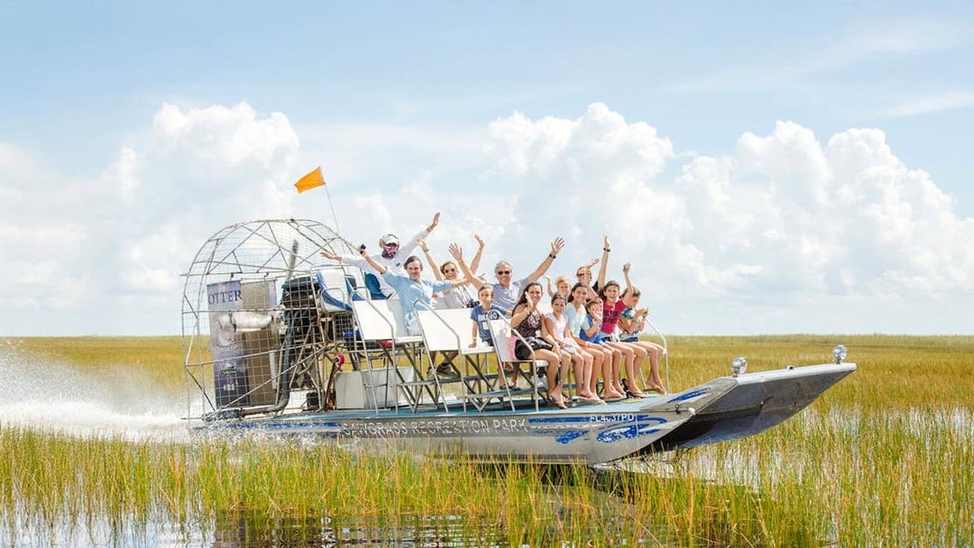 Group enjoying an Everglades private airboat tour through marshlands.