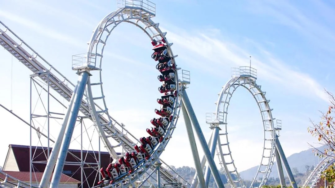 Steel roller coaster with multiple loops against a clear sky.