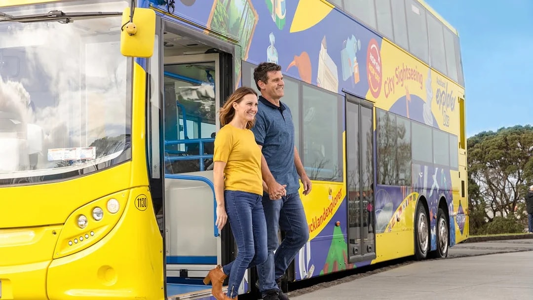 Couple exiting Auckland Explorer Bus on hop-on-hop-off city tour.