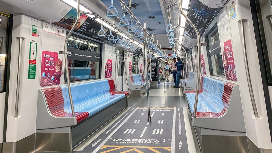 MRT train interior in Singapore with blue and red seats, overhead handles, and safety signage.