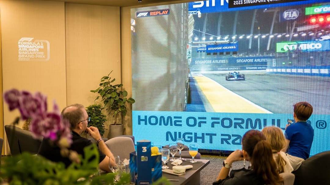 Guests watching Formula 1 Singapore Grand Prix highlights on a large screen in a hospitality suite.