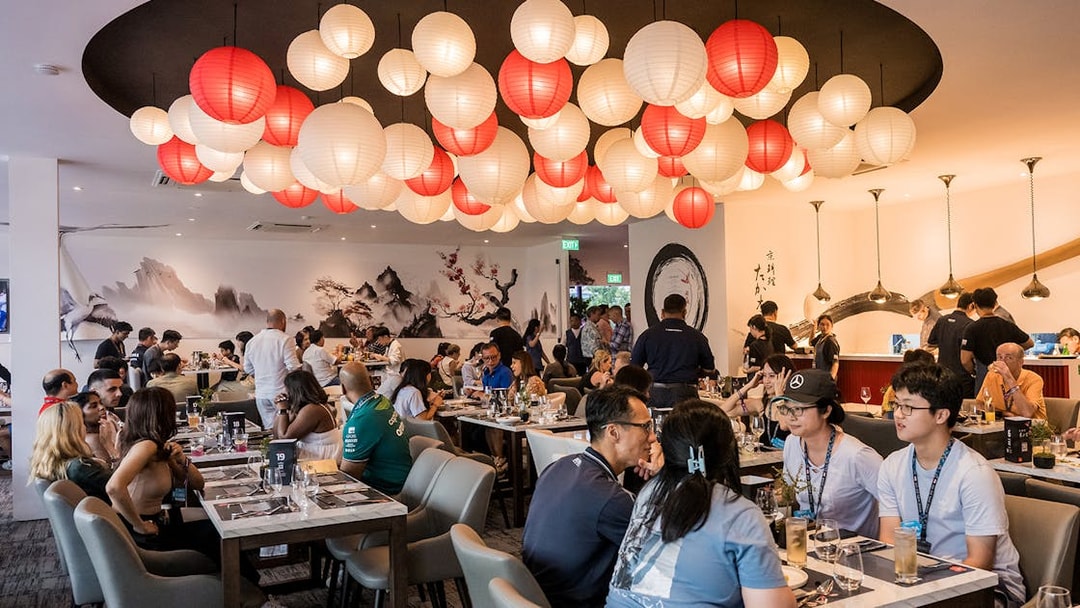 Guests dining in a stylish venue with red and white lanterns at the Singapore Grand Prix 2025 hospitality event.