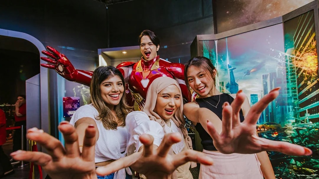 Three people posing with Iron Man wax figure at Madame Tussauds Singapore.
