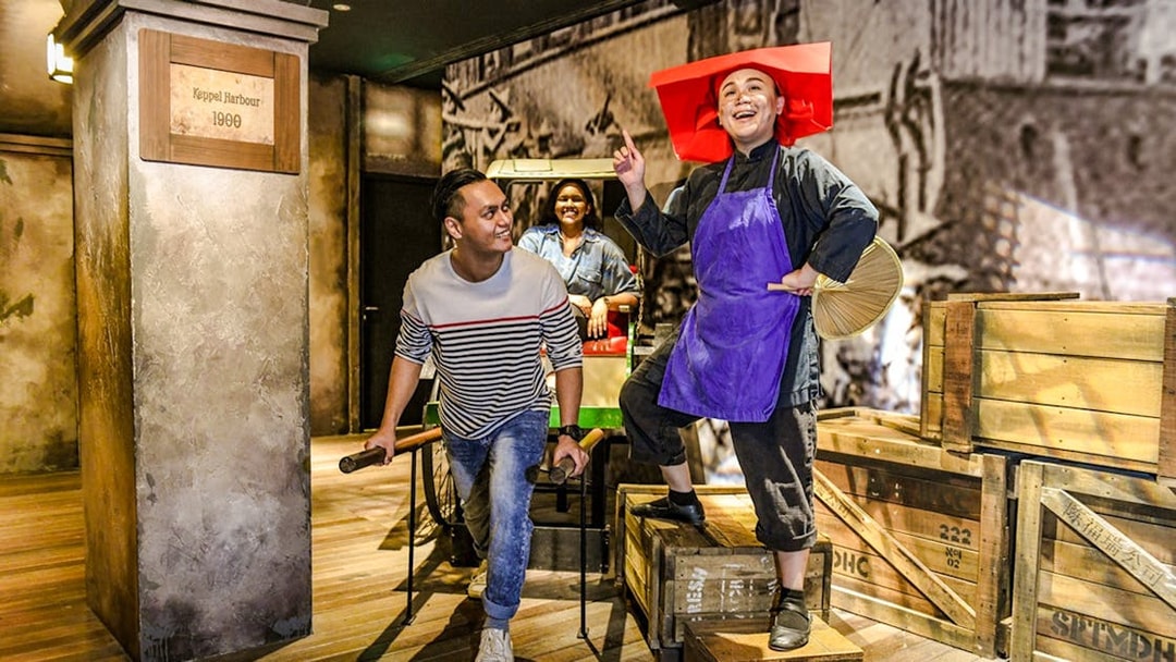 Man pulling a rickshaw with passengers at Madame Tussauds Singapore, depicting early 1900s Keppel Harbour.