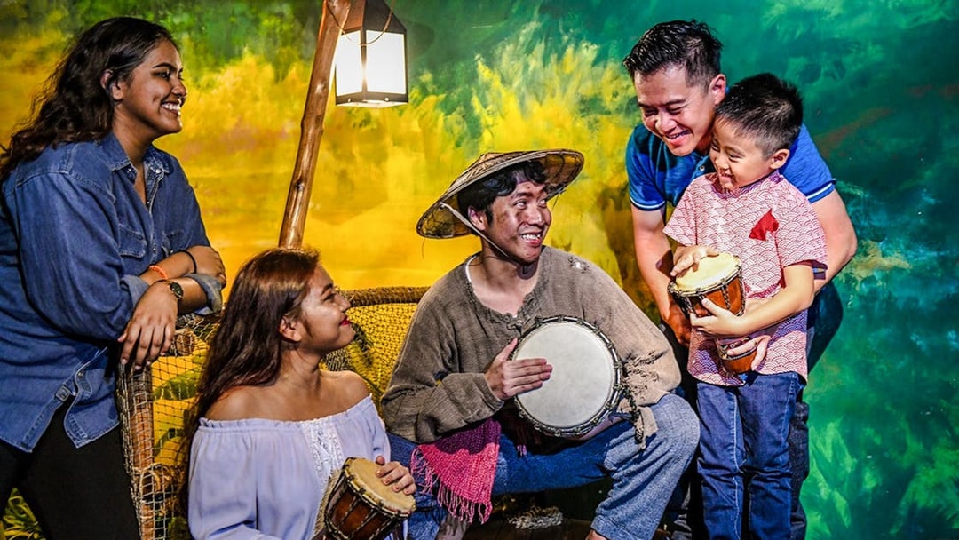 People engaging with a historical drumming exhibit at Madame Tussauds Singapore.