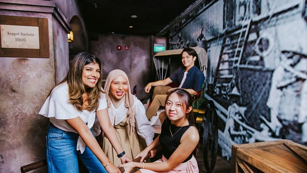 Visitors engaging with a historical rickshaw exhibit at Madame Tussauds Singapore.