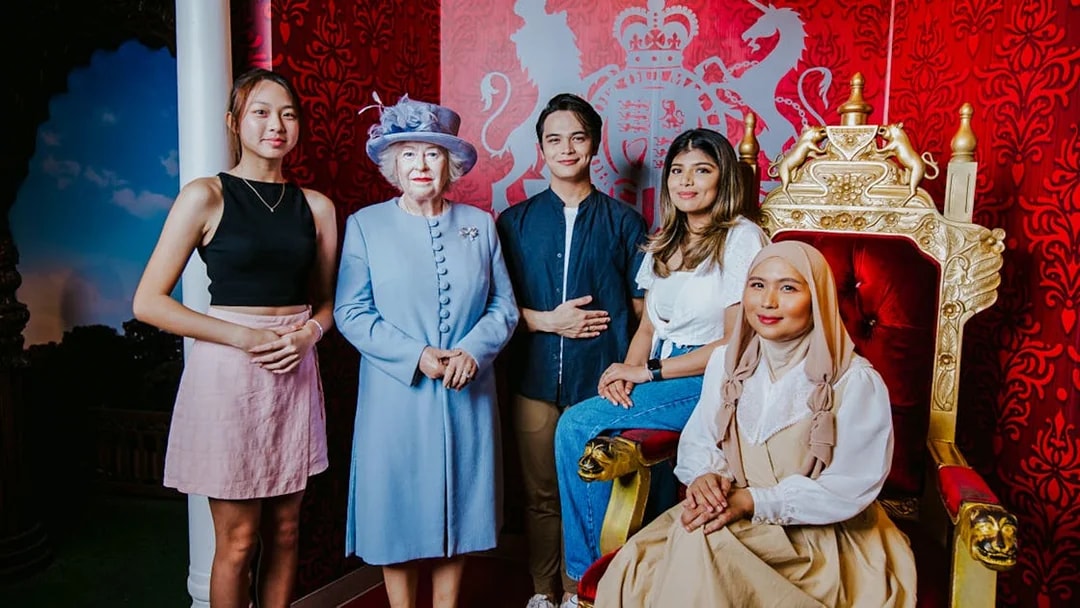 Tourists with Queen wax figure at Madame Tussauds Singapore.