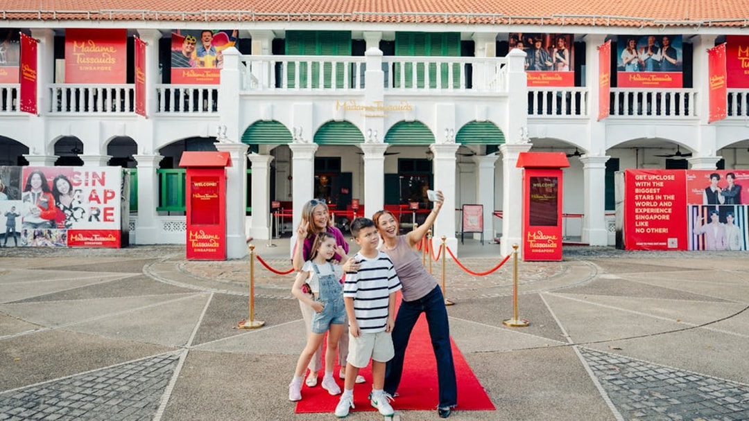 Family taking a selfie outside Madame Tussauds Singapore entrance.