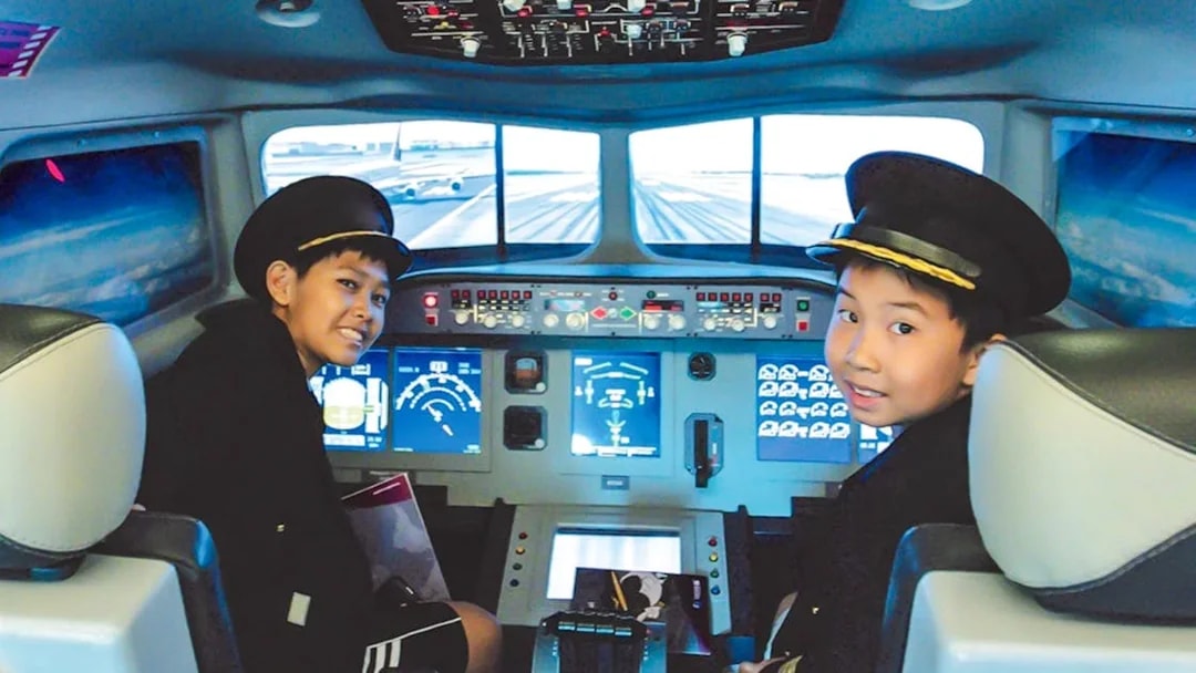 Kids in pilot uniforms in airplane cockpit simulator at KidZania.