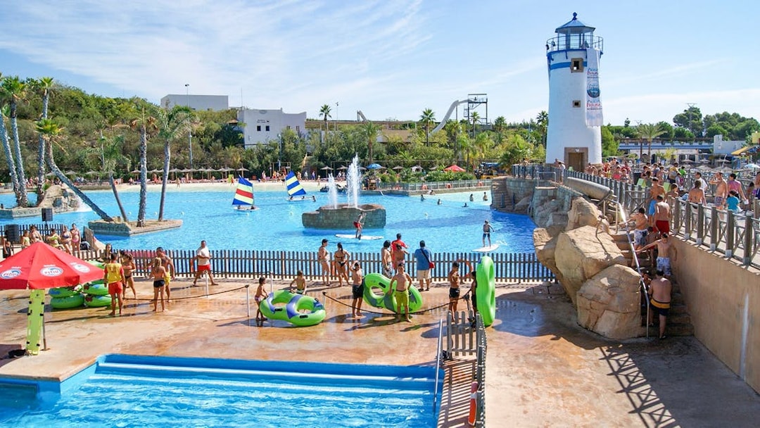 Visitors enjoying the water park at Terra Natura Benidorm with a lighthouse and pool activities.