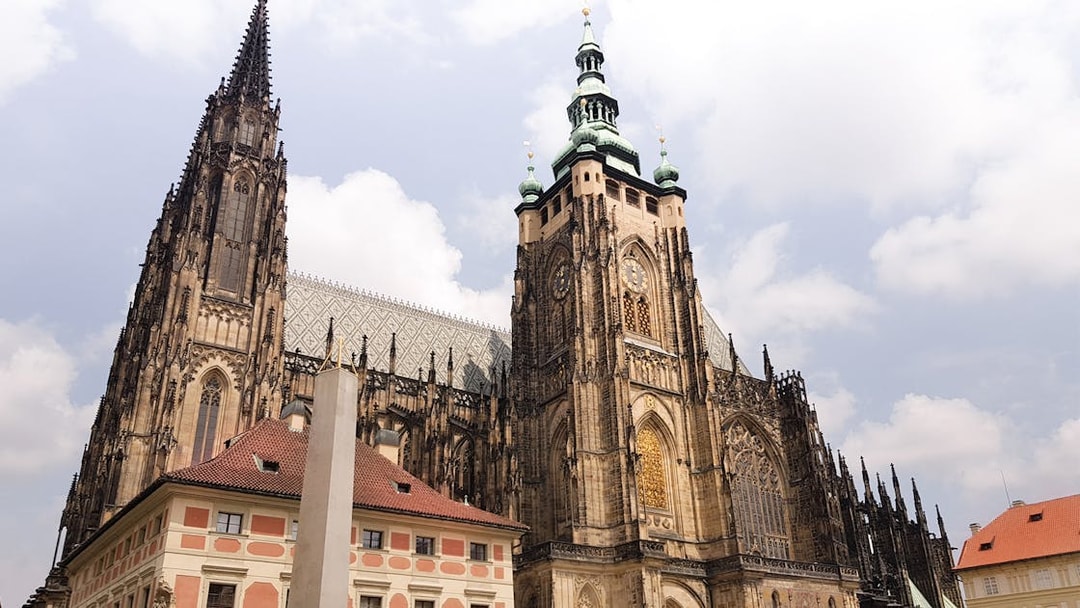 Prague Castle exterior with gothic architecture under a cloudy sky.