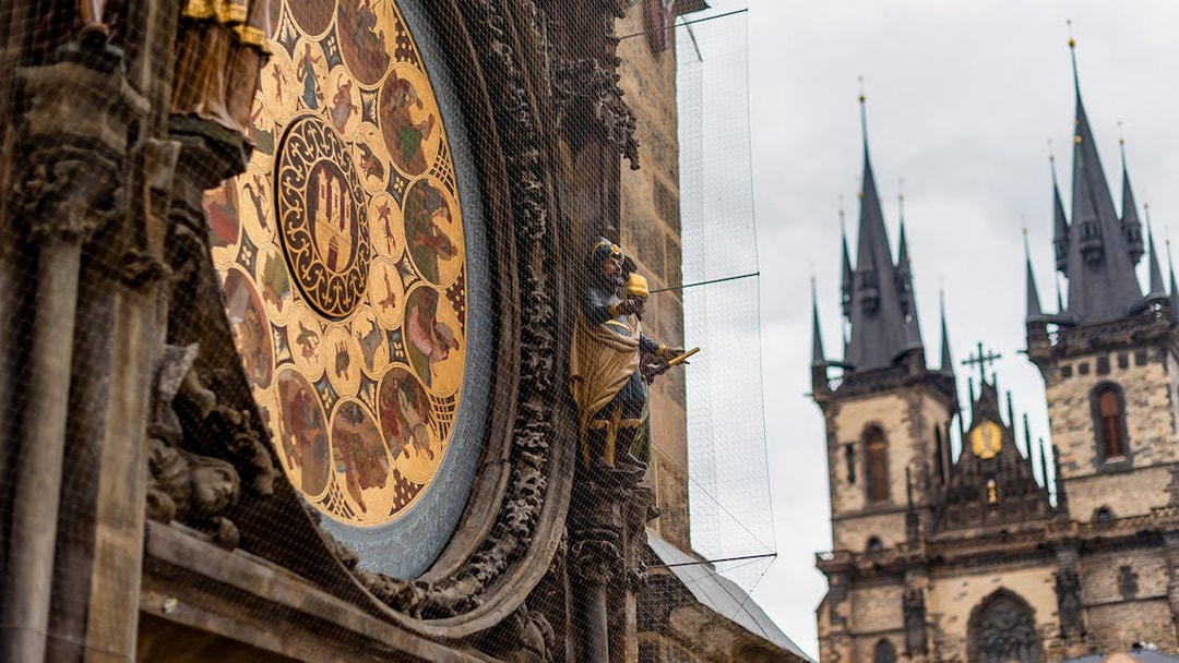 Astronomical Clock detail with Prague Castle spires in the background.