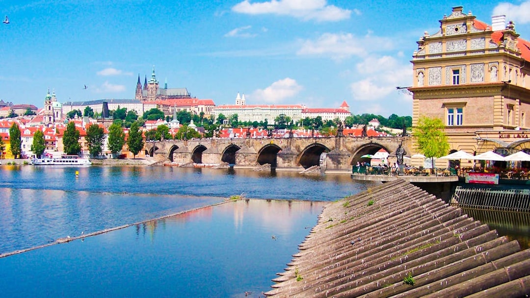 Prague's Charles Bridge with Prague Castle in the background on a sunny day.