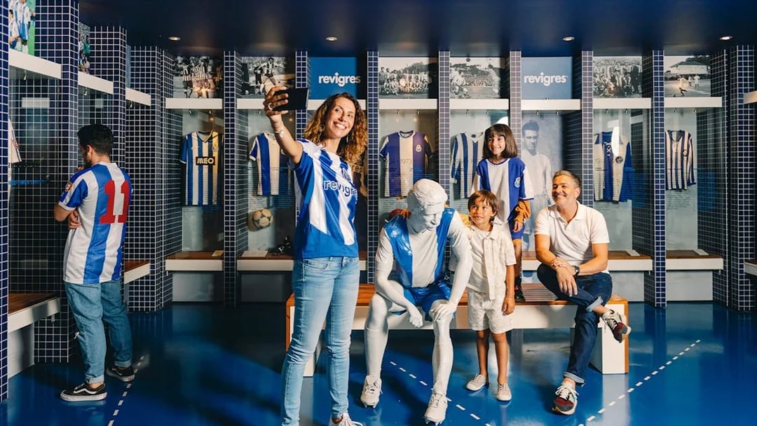 Visitors taking photos at FC Porto museum exhibit with jerseys and statue.
