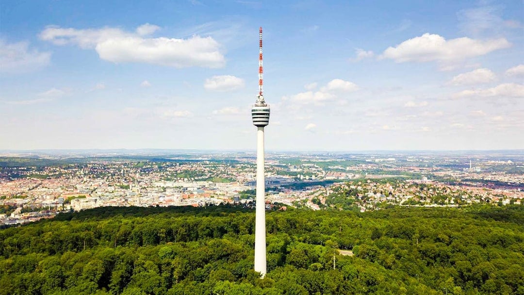 Fernsehturm Stuttgart tower overlooking cityscape and forest.