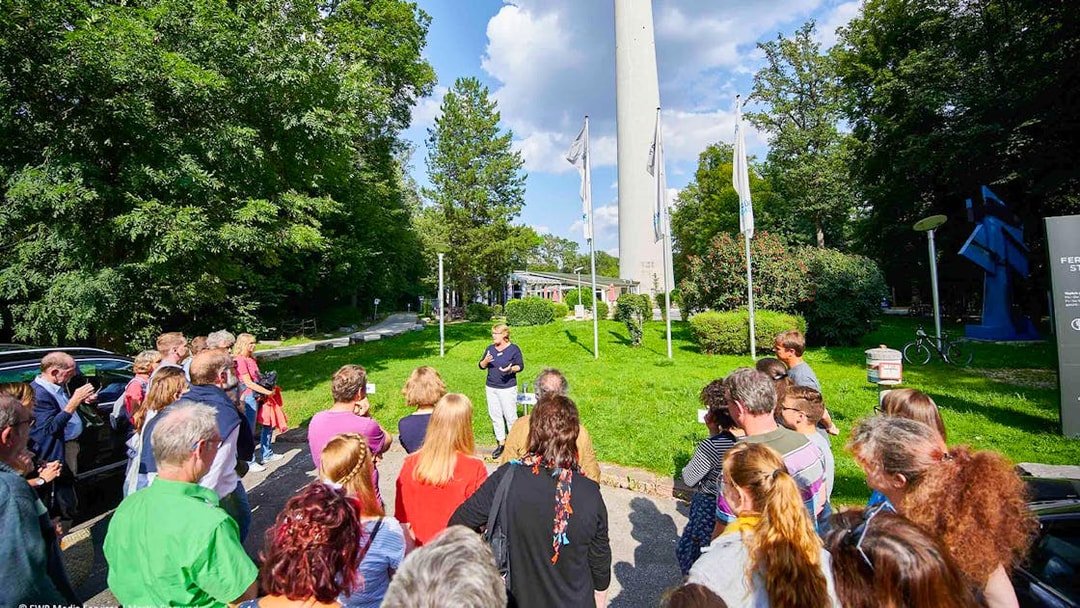 Group tour at the base of Fernsehturm Stuttgart, guide speaking to visitors.